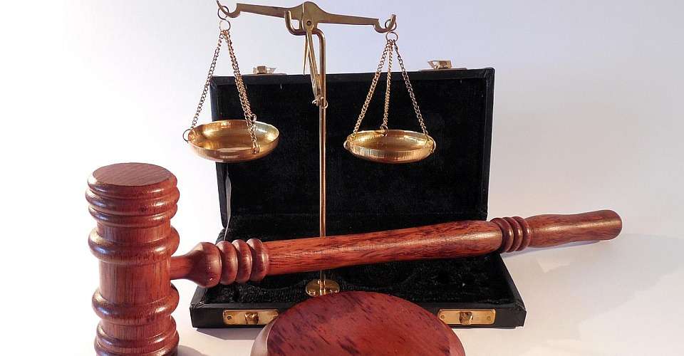 Un ciocan (ciocan de lemn) folosit de judecător într-o sală de judecată, împreună cu un bloc de sunet din lemn și o balanță de aur - toate simbolizând judecata.